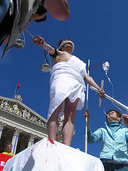 Als Justizia verkleideter Aktivist, dem Blut abgezapft wird